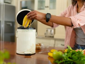 Midsection of young african american woman putting banana peel in compost bin at home