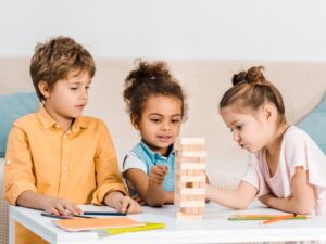 cute little multiracial children playing with wooden blocks on table