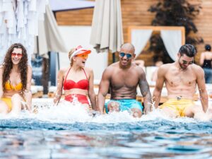 group of young happy friends resting in swimming pool