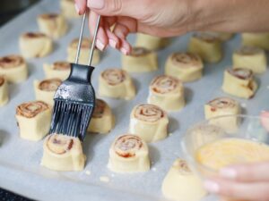 A woman backing a cinnamon roll cookies.