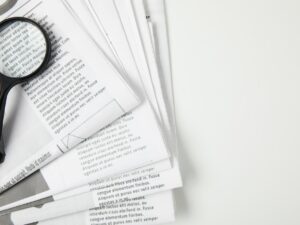 top view of magnifying glass and newspapers on grey, information concept