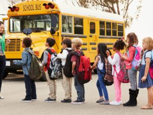 Teacher and a group of elementary school kids at a bus stop