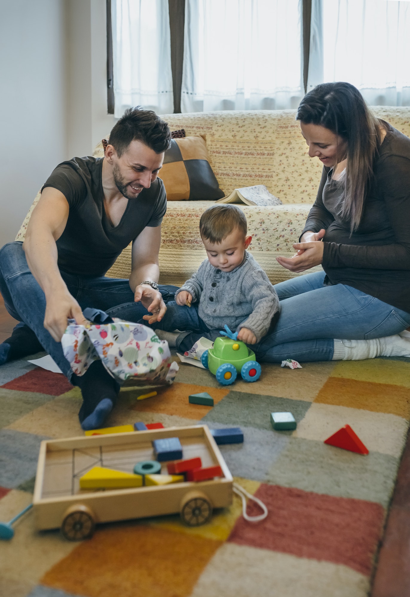 Parents with their little son opening a gift