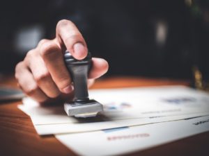 Close-up Of A Person's Hand Stamping With Approved Stamp On Text Approved